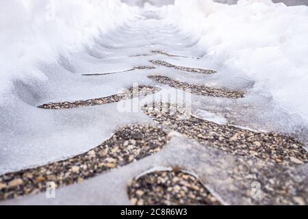 Traces d'un pneu de tracteur sur de l'asphalte neigeux sur une route en hiver. Banque D'Images