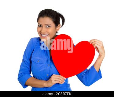 Gros plan portrait de la jolie femme souriante tenant le cœur rouge à la poitrine rêvant, dans l'amour, isolée sur fond blanc. Émotion positive du visage Banque D'Images