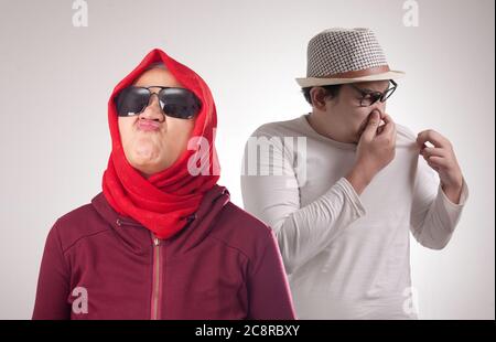 Drôle d'homme asiatique embarrassé devant la femme avant d'avoir une mauvaise odeur de corps, l'homme sentant son propre corps Banque D'Images