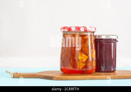 Deux pots en verre avec confiture de pomme et de framboise sur un panneau en bois Banque D'Images