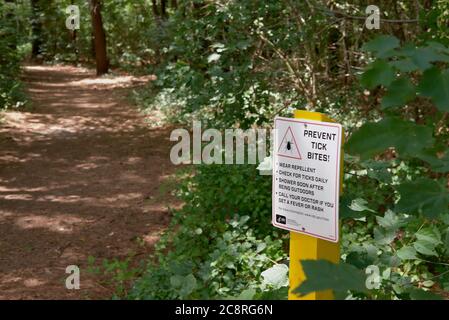 Un panneau de signalisation signale aux randonneurs la menace de tiques le long du sentier dans la zone naturelle de Chapel Branch, près de Seaford, DE. Banque D'Images