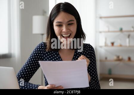 Une fille asiatique surjoyée, excitée par de bonnes nouvelles dans la lettre Banque D'Images