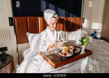 belle femme appréciant son petit déjeuner dans un lit confortable. Concept de service d'étage de l'hôtel. Photo de haute qualité Banque D'Images