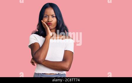 Jeune fille indienne portant des vêtements décontractés pensant fatigué et ennuyé avec des problèmes de dépression avec les bras croisés. Banque D'Images