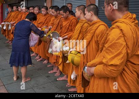 Les moines novices de Wat Mahathe à Bangkok, en Thaïlande, pendant leur matinée traditionnelle, et avec des bols d'alms alignés pour recevoir des alms Banque D'Images