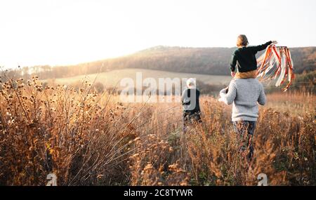 Vue arrière de la famille avec petite fille sur une promenade dans la nature automnale. Banque D'Images