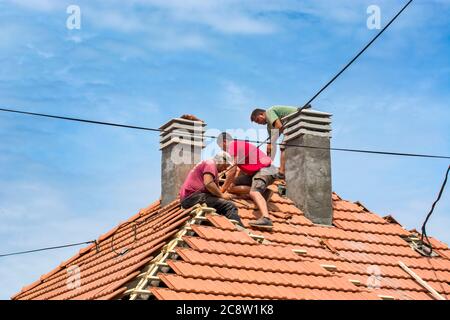 Zrenjanin, Serbie, 23 juillet 2020. Un groupe de maîtres travaille sur le toit d'une maison privée pour remplacer un vieux carrelage. Ils ont une belle journée et stable Banque D'Images