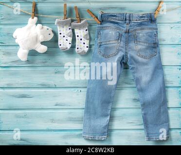 Jeans, chaussettes et ours blanc en peluche pour bébé garçon sur une corde à linge Banque D'Images