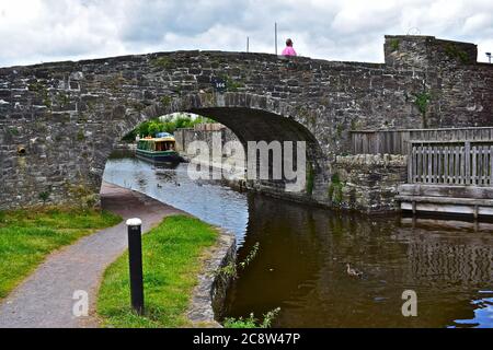 Un vieux pont en pierre au-dessus du canal Monbucshire et Brecon, juste avant le bassin du canal, au centre de Brecon, bateau sur le canal aux amarres. Banque D'Images