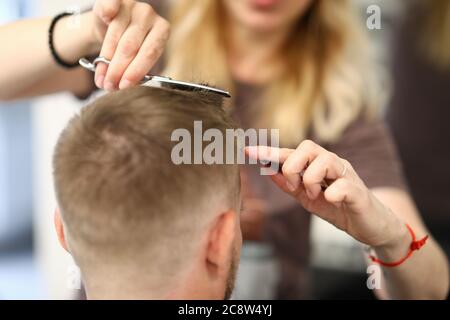 Une femme coiffante coupe les cheveux de l'homme dans un salon de beauté Banque D'Images