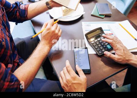 Image rapprochée des amis qui font la liste d'emballage et calculent les dépenses lors de la planification du voyage ensemble Banque D'Images