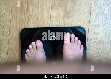 Obèse homme point de vue regardant ses pieds et IMC sur les balances Banque D'Images