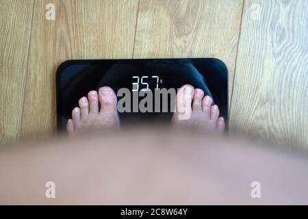 Obèse homme point de vue regardant ses pieds et IMC sur les balances Banque D'Images