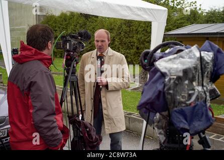 Amstetten, Autriche - avril 29 2008: TV News reporter modérateur dans la pluie battante sur le cas Fritzl Cellar. Banque D'Images