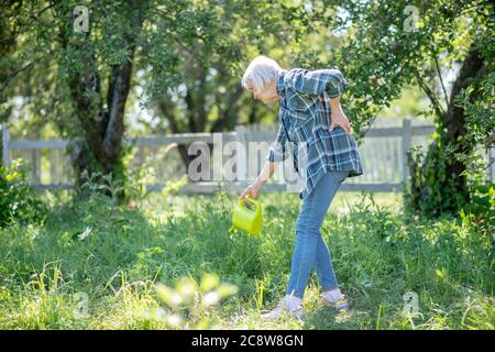 Femme ayant une douleur dorsale arroser le jardin Banque D'Images