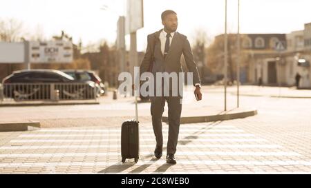 Homme d'affaires africain avec Travel Suitcase Crossing Road à City, Panorama Banque D'Images