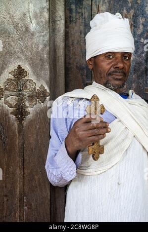 Debre Sina Beta Maryam église, lac Tana, Bahir Dar, Ethiopie. Un prêtre pose majestueusement avec sa croix à la porte du monastère de Birgida Maryam sur l'une des îles du lac Tana. Le lac Tana, le plus grand lac d'Éthiopie, est la source du Nil Bleu d'où il commence son long voyage à Khartoum et à la Méditerranée. | utilisation dans le monde entier Banque D'Images