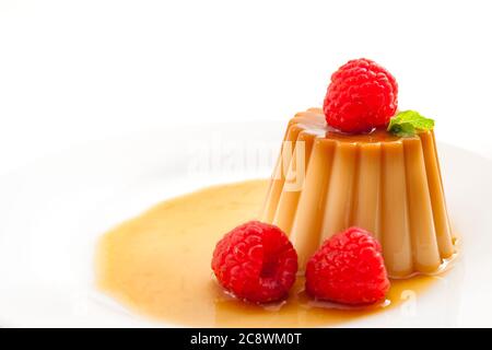 Dessert maison et sucreries douces avec gros plan sur le caramel crème, le flan, ou le pudding au caramel recouvert de sirop doux et de framboises iso Banque D'Images