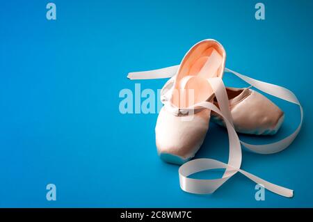 Concept de danse de ballet avec une paire de chaussures en soie isolées sur fond bleu clair minimaliste Banque D'Images