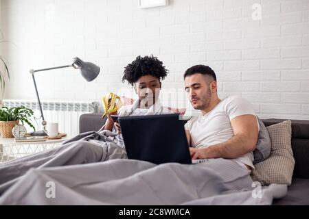 Un jeune couple surfant sur Internet dans le lit Banque D'Images