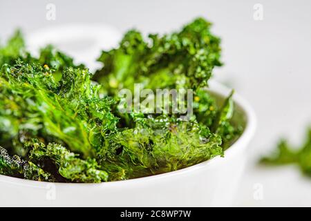 Croustilles vertes avec sel dans un bol blanc. Concept alimentaire végétalien sain. Banque D'Images