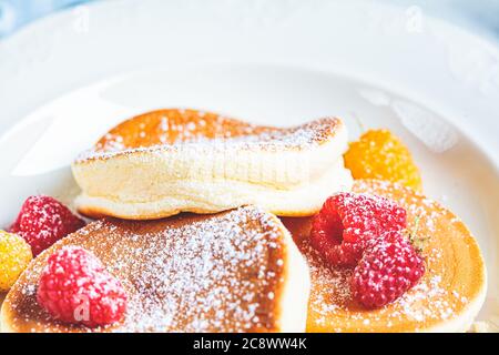 Crêpes japonaises moelleuses aux framboises dans une assiette blanche, fond blanc. Concept de cuisine japonaise. Banque D'Images