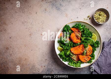 Salade de patates douces cuite au four avec kale dans un bol, fond sombre, espace de copie. Concept alimentaire végétalien. Banque D'Images