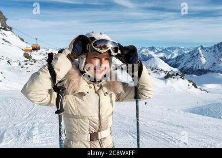 Jeune adulte beau heureux attrayant caucasien souriant skieur femme portrait teke sur le masque sur le pic de la montagne montrant le panorama de la station de ski Banque D'Images