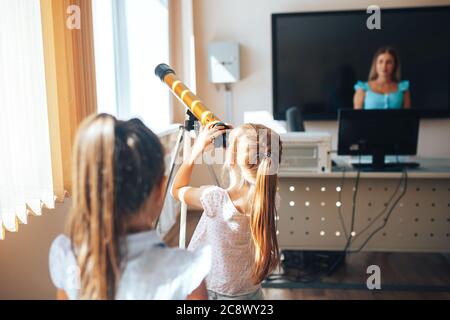 Deux écolières regardent à travers un télescope dans une leçon d'astronomie, de retour à l'école, l'éducation des enfants Banque D'Images