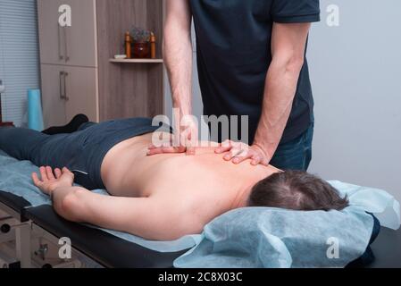 Le thérapeute physique fait un massage profond sur un homme de dos . Banque D'Images