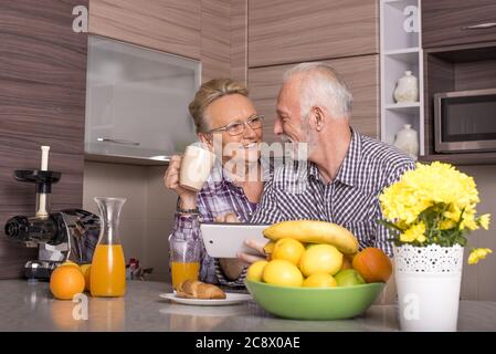 Heureux couple de personnes âgées de race blanche debout derrière le comptoir de la cuisine Banque D'Images