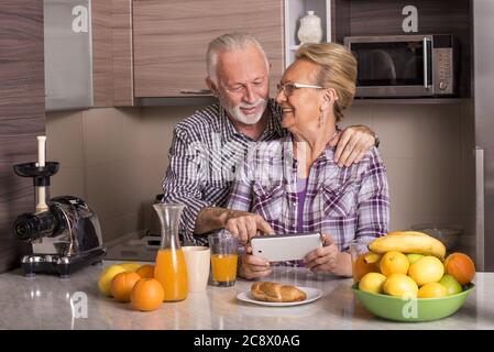 Heureux couple de personnes âgées de race blanche debout derrière le comptoir de la cuisine Banque D'Images