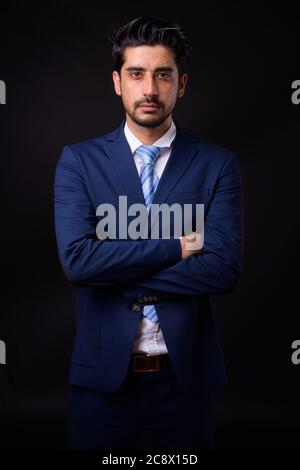 Jeune homme d'affaires persan beau barbu sur fond noir Banque D'Images