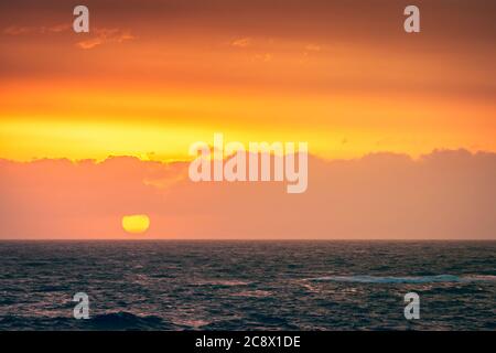 Grand soleil jaune tombant derrière la mer à Christies Beach pendant le coucher du soleil, Australie méridionale Banque D'Images