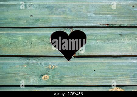 Clôture en bois vert avec péephole en forme de coeur. Porte avec trou en forme de coeur sculpté. Banque D'Images