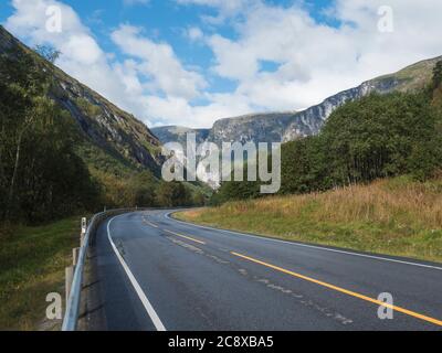 Route sinueuse E136 avec massif de montagne Trolltindene, mur de Trollveggen, la plus haute montagne verticale d'Europe vallée de Romsdal, Norvège. Ciel bleu Banque D'Images