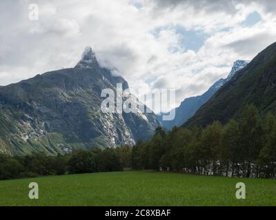 Vue sur le massif de montagne Trolltindene, Troll Wall Trollveggen, la plus haute montagne verticale d'Europe, vallée de Romsdal, Norvège. Herbe verte, ciel bleu Banque D'Images