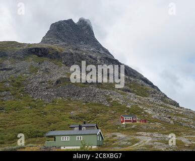Cabanes de montagne en bois vert et rouge au massif de Trolltindene, Troll Wall Trollveggen, dans la vallée de Romsdal, en Norvège. Nuages ciel blanc nuageux. Été Banque D'Images