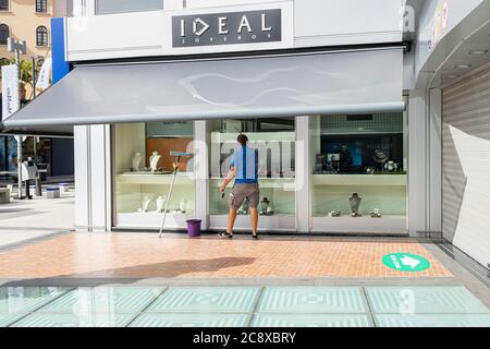 Plaza Del Duque, Costa Adeje, Tenerife, Iles Canaries, Espagne. 27 juillet 2020. Le centre commercial de luxe, Plaza del Duque, a rouvert la plupart des magasins aujourd'hui après quatre mois de fermeture en raison du virus Covid 19, Corona verrouillage. Un homme nettoie la fenêtre d'un magasin en préparation à l'ouverture. Le tourisme revient lentement aux îles, les hôtels et les entreprises touristiques commencent à s'ouvrir à nouveau. Banque D'Images