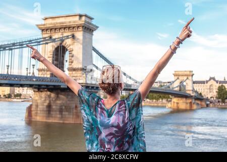 Bonne jeune femme urbaine bras élevés en ville, vue arrière, à Budapest, Hongrie Banque D'Images