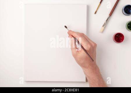 Gouache, pinceaux, toile blanche sur fond blanc. Dessin à la main sur toile blanche. Copier l'espace. Vue de dessus. Pose à plat. Banque D'Images