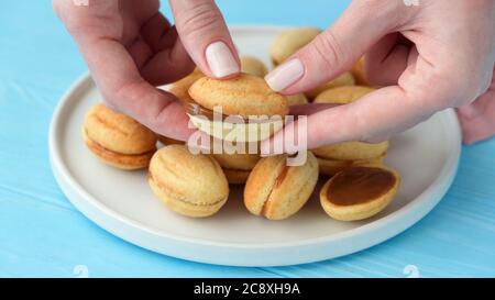 Biscuits en forme de noyer avec garniture au caramel dulce de leche. Cuisine russe. Biscuit Oreshki dans les mains des femmes Banque D'Images