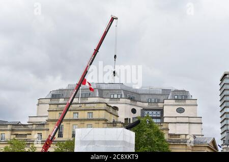 Londres, Royaume-Uni. 27 juillet 2020. Une grue lève un géant Fly sur une réplique de crème fouettée surmontée d'une cerise à Trafalgar Square, dans le centre de Londres. La sculpture de Heather Phillipson, intitulée THE END, devait être dévoilée le 26 mars mais retardée en raison de la crise de Covid-19. Son drone transmettra un flux en direct de la place qui peut être regardé sur un site Web dédié. Crédit : SOPA Images Limited/Alamy Live News Banque D'Images