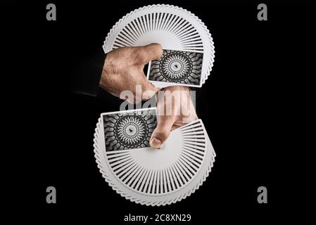 Ventilateur de cartes à jouer personnalisé. Magicien tenant deux ponts sur un fond noir. Slating, shuffling, agilité, trick, art Banque D'Images