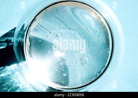 Texture de gel crème claire et cosmétique comprimée. Photo de gros plan du gel d'aloe vera transparent avec des bulles dans un bol en verre sur fond bleu. Soin de la peau, guérir Banque D'Images