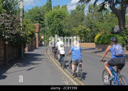 Une famille qui fait du vélo sur une route tranquille à Shepperton Surrey, au Royaume-Uni Banque D'Images