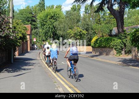 Une famille qui fait du vélo sur une route tranquille à Shepperton Surrey, au Royaume-Uni Banque D'Images