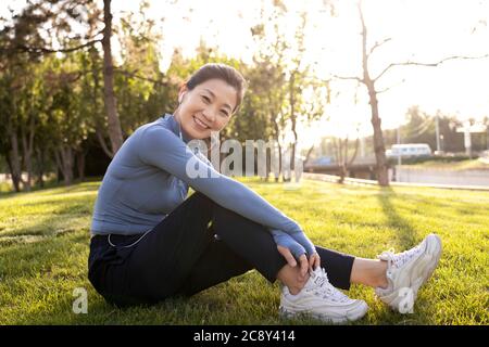 Femme d'âge moyen assise sur l'herbe Banque D'Images