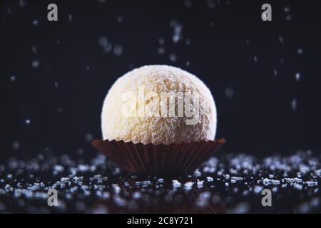 Grande Candy de noix de coco ou boule à gâteau avec garniture au chocolat blanc dans une assiette isolée Banque D'Images