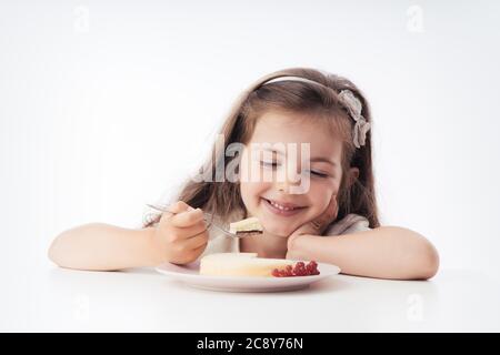 Belle petite fille surprise d'un savoureux cheesecake. Gâteau prêt à manger pour enfant. Banque D'Images